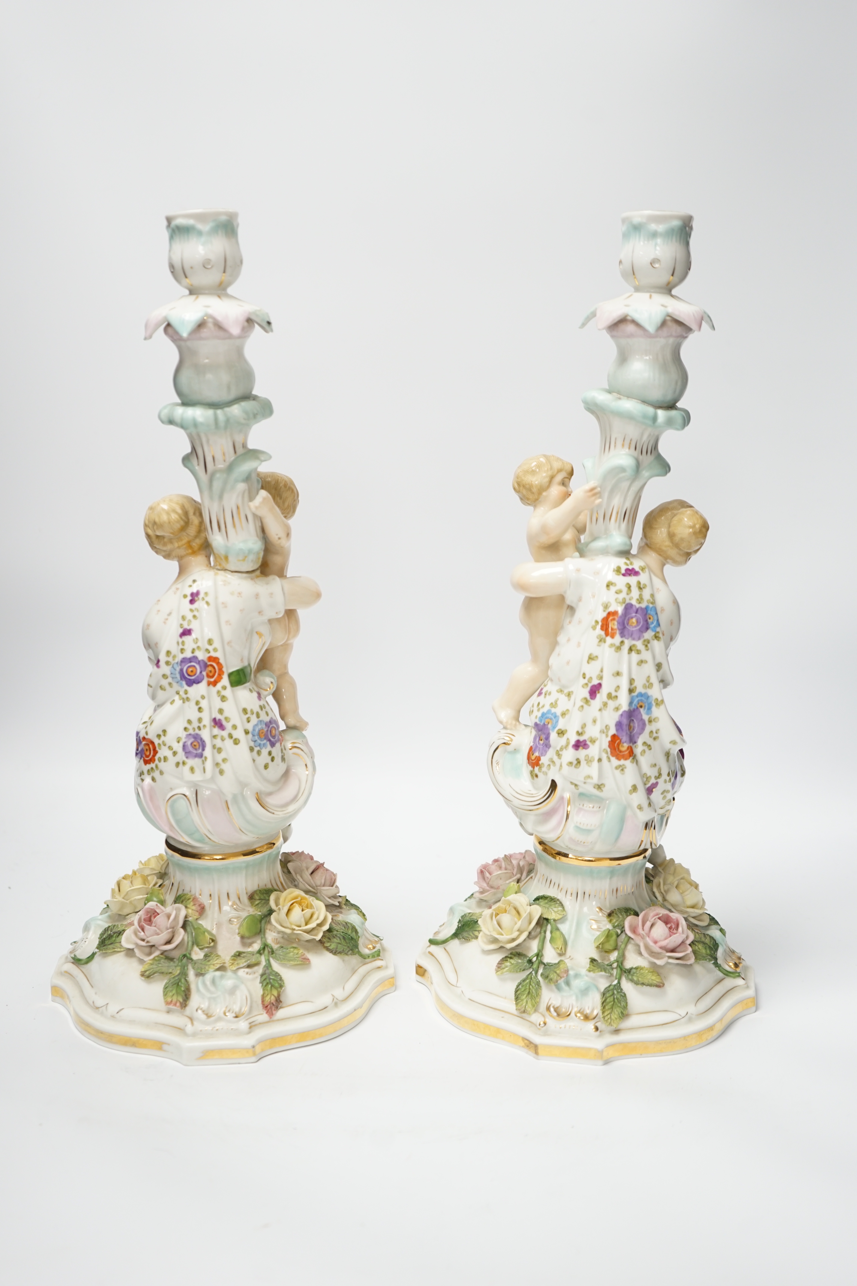 A pair of German floral encrusted porcelain candlesticks of a mother and child group, 38cm high